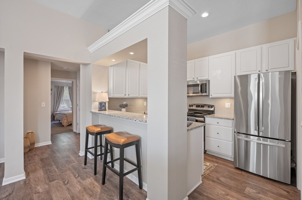 A kitchen with white cabinets and a stainless steel refrigerator.