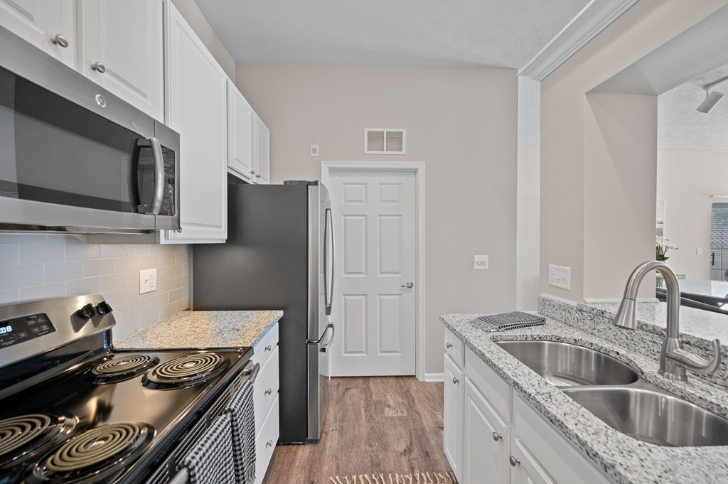 A kitchen with a black refrigerator and stove top oven.