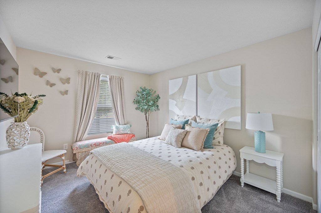 A bedroom with a large bed and a white chair.