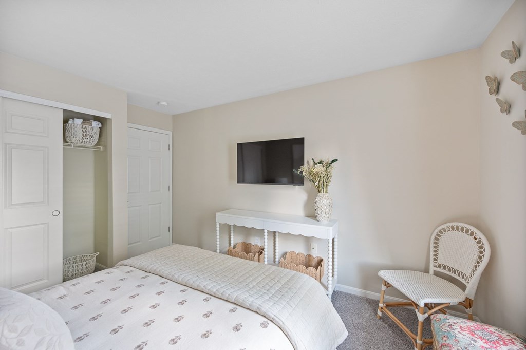 A bedroom with a bed, chair, and television.