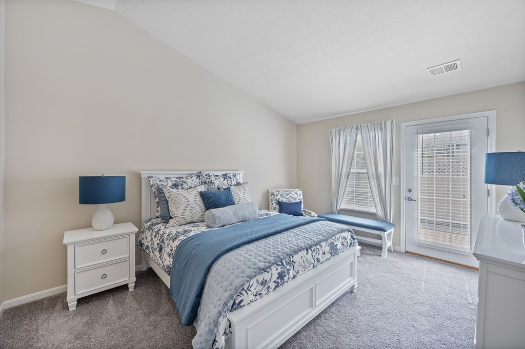 A bedroom with a bed, nightstand, and window.