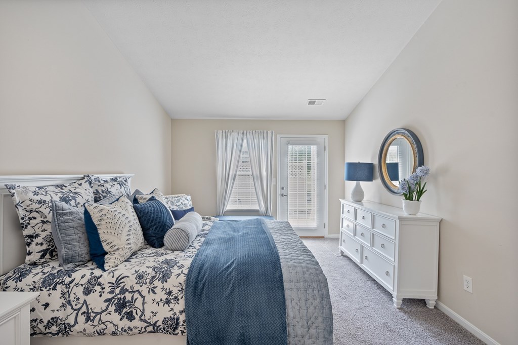 A bedroom with a large bed and a dresser with a mirror.
