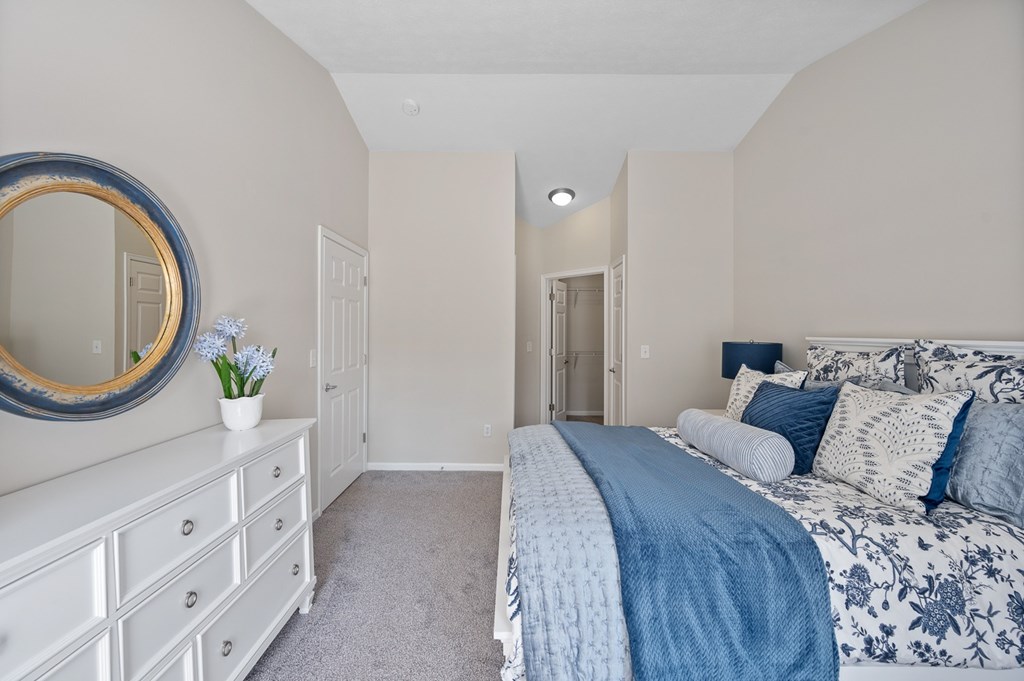 A bedroom with a bed, dresser, and mirror.