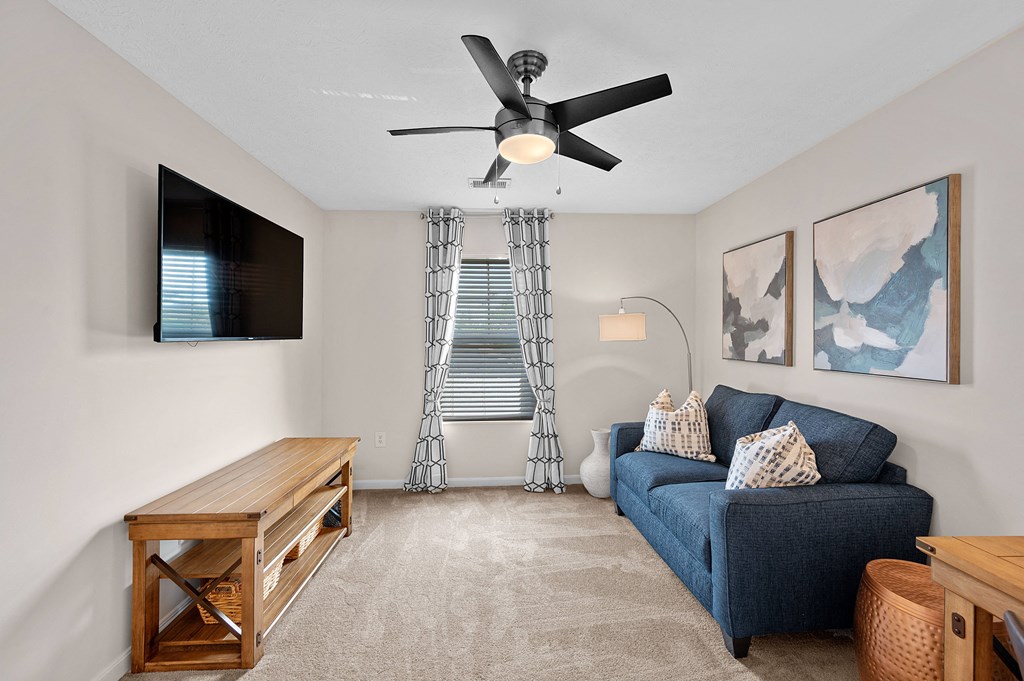 Living room with a blue couch and a ceiling fan at Four Bridges, Liberty Township, Ohio