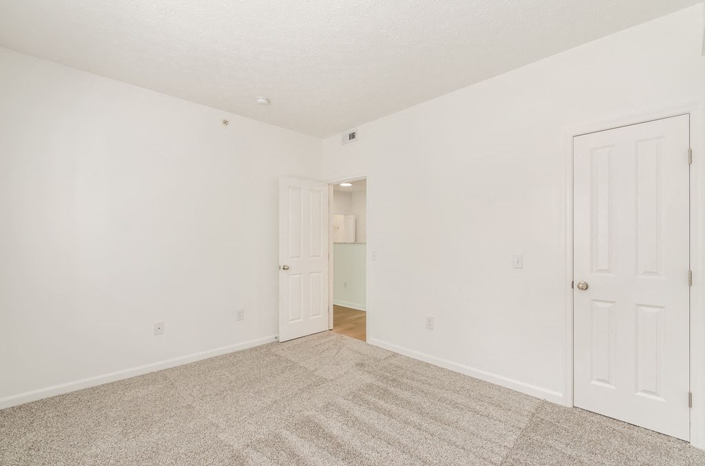 a bedroom with white walls and carpet and a door to a closet at Prescott Place, Columbus
