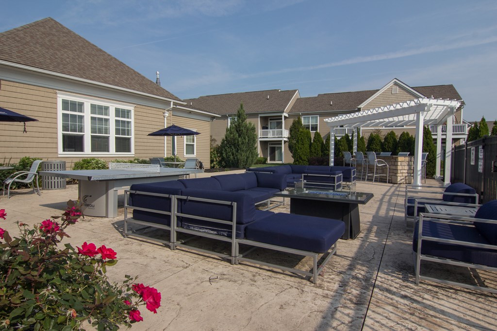 a large patio with blue couches and chairs and a table with a ping pong table  at Grove City Summit, Ohio