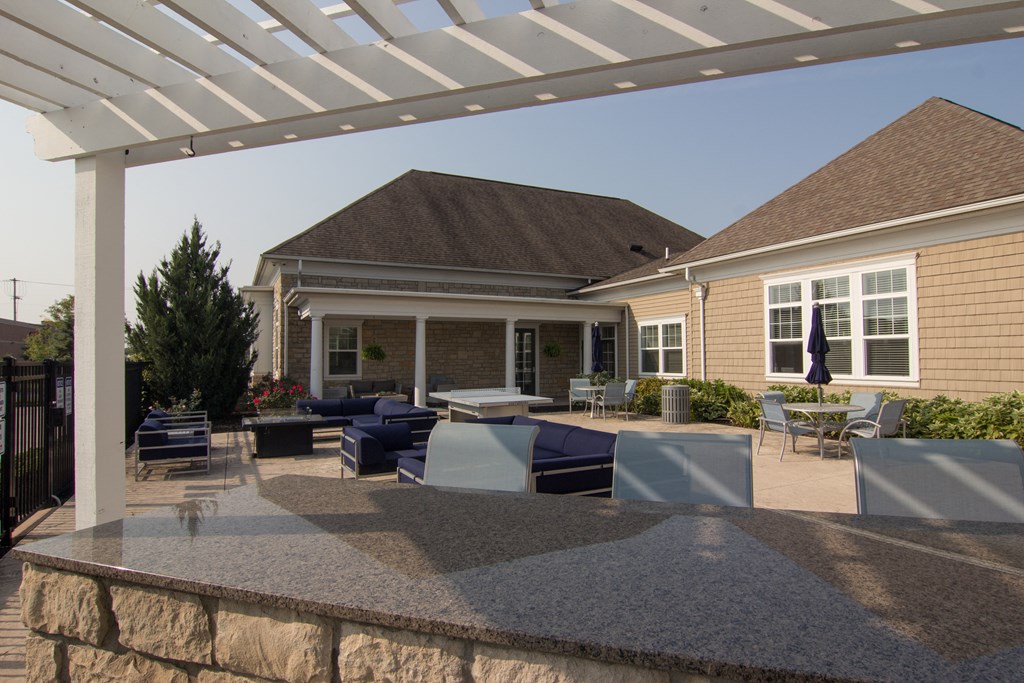 an outdoor entertaining area with a stone wall and a white pergola  at Grove City Summit, Grove City