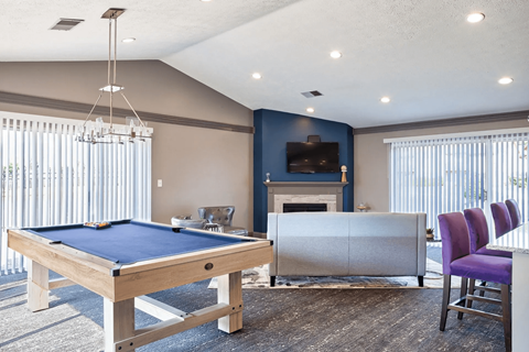 A pool table is in the middle of a room with a fireplace and a TV.
