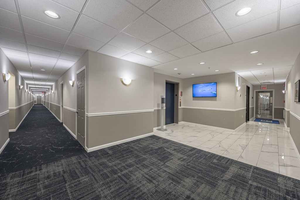 an empty hallway with a tv on the wall and a door