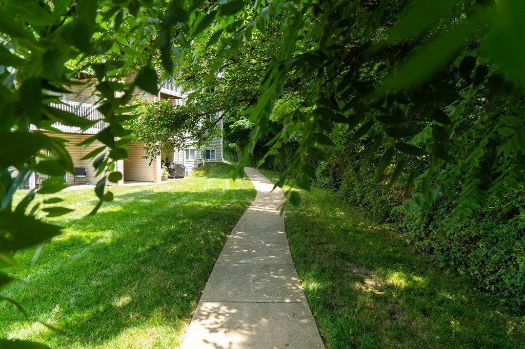 a walkway through the grass in front of a house