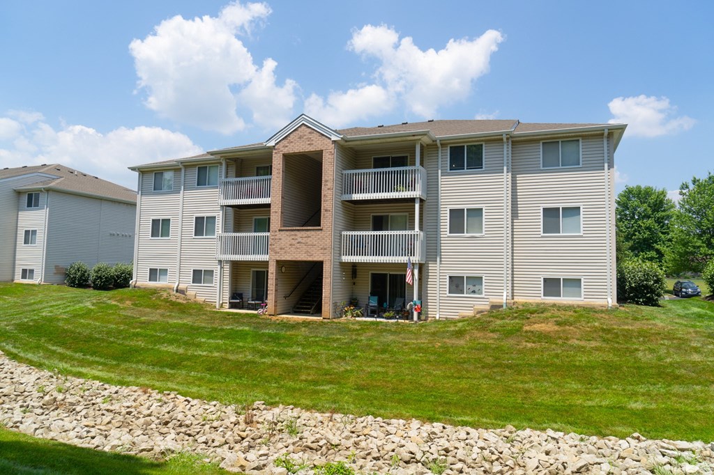 an apartment building on a hill with a grass lawn