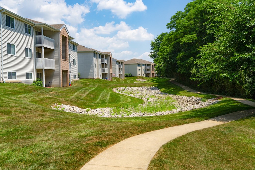 a sidewalk leading to an apartment building with a landscaped yard