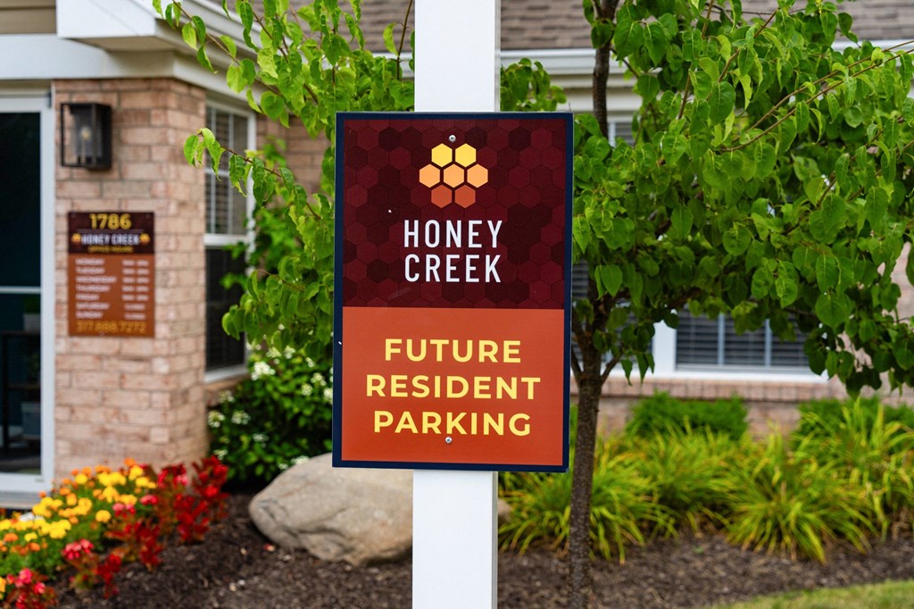 a sign for honey creek future resident parking in front of a house