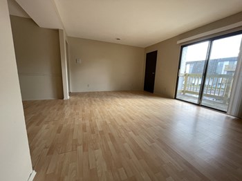 an empty living room with wood floors and a sliding glass door - Photo Gallery 14