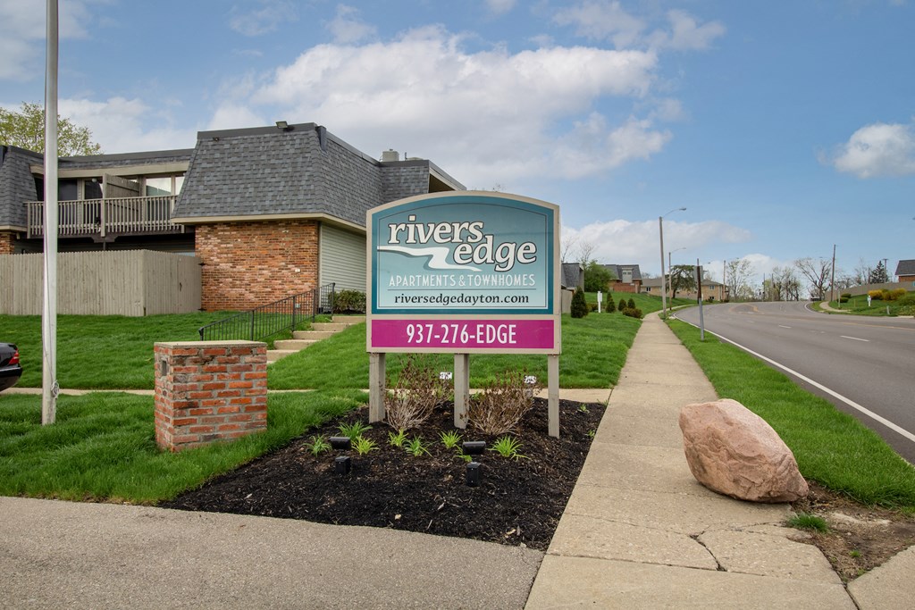 a sign for rivers edge apartments on the side of the street