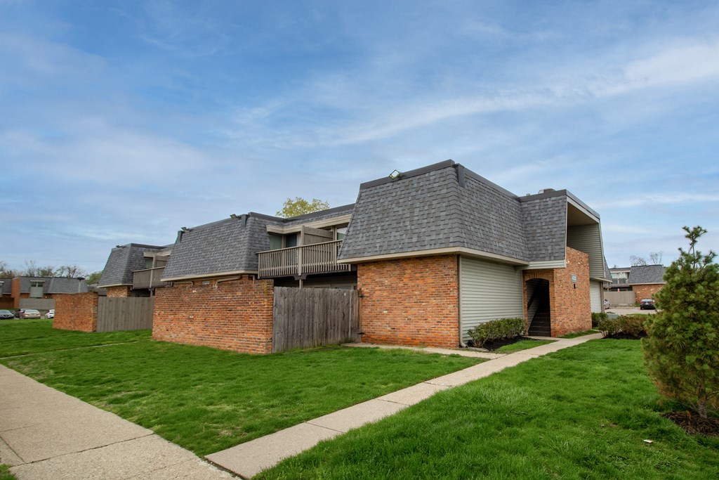 a brick house with a grey roof and a sidewalk