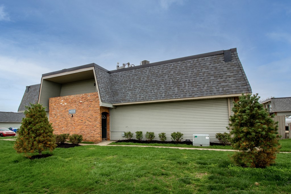 the front of a house with a gray roof and a green lawn