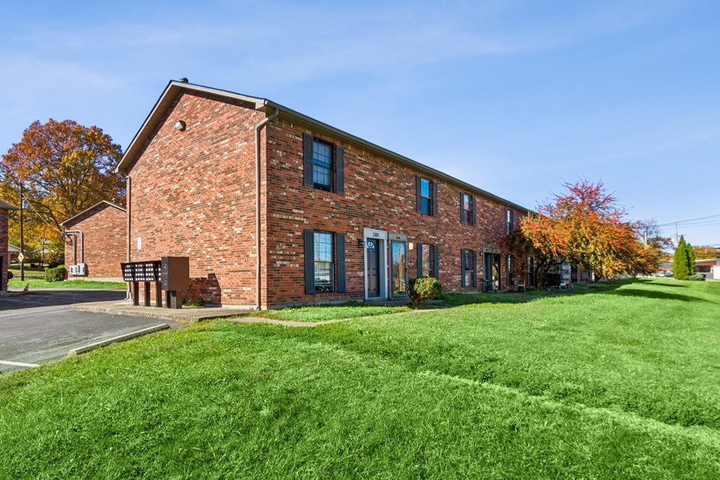 A red brick building with a green lawn in front.