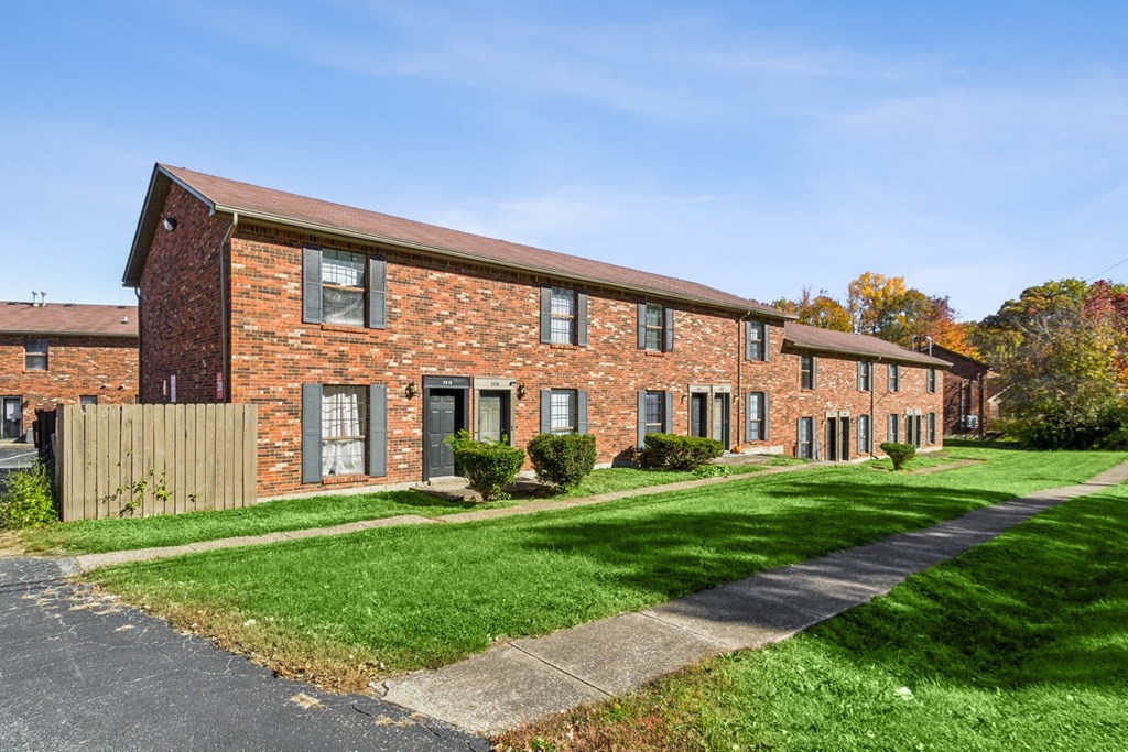 A red brick building with a green lawn in front.
