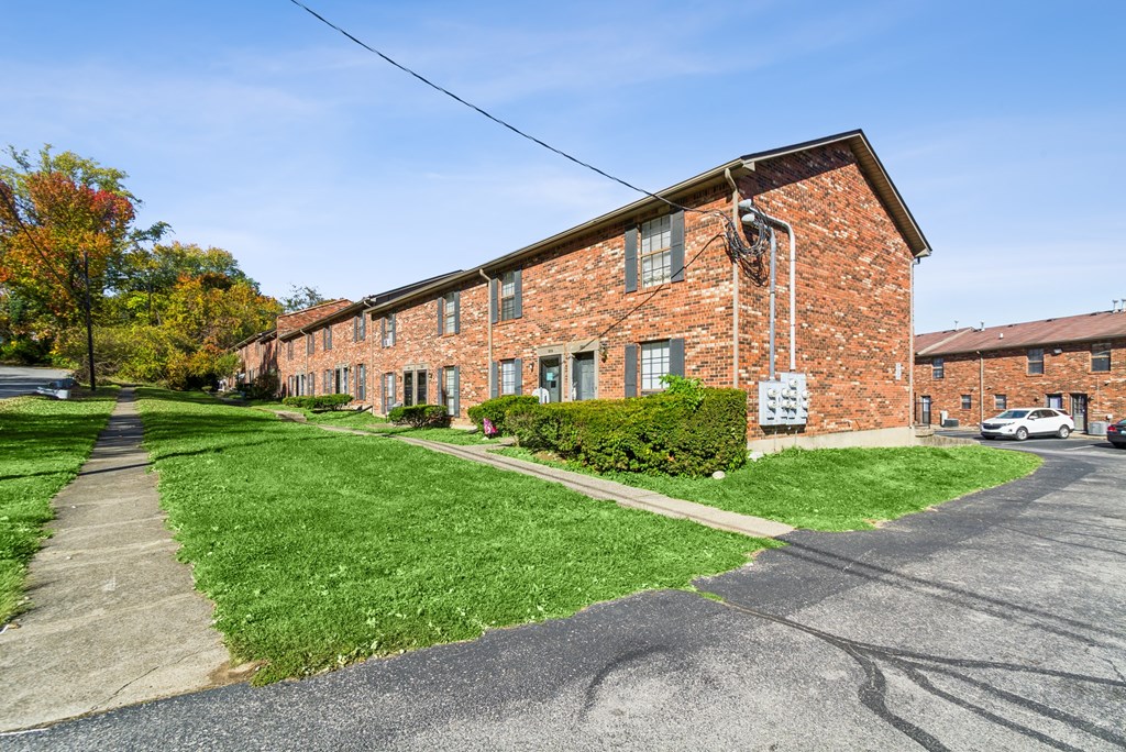 A red brick building with a green lawn in front.