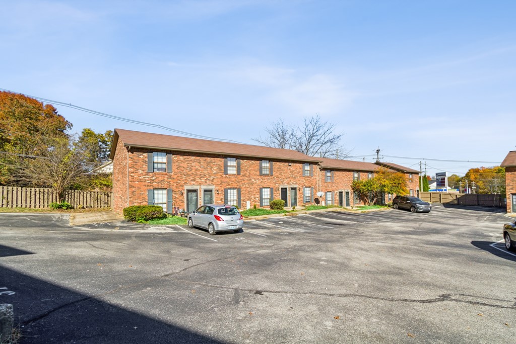 A parking lot with a building in the background and a car parked in the lot.