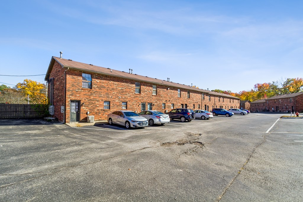 A parking lot with cars and a brick building.