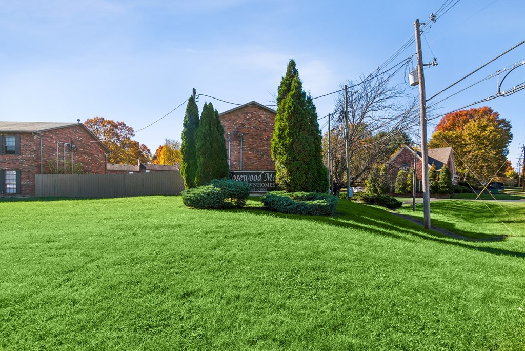 A green lawn in front of a brick building with a sign that says