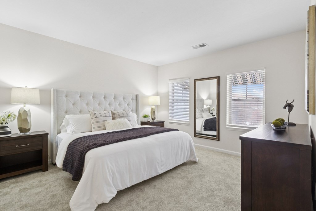 A bedroom with a large bed, a nightstand, and a dresser.