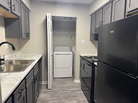 A black refrigerator is on the right side of a kitchen.