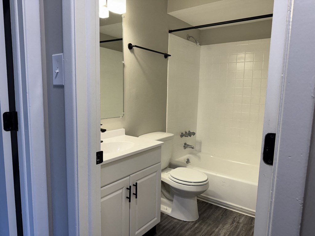 A white toilet is in a bathroom with a white sink and a white bathtub at Quail Run Apartments, Columbus, Indiana