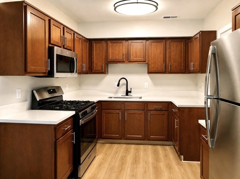 A kitchen with wooden cabinets and a stainless steel refrigerator.