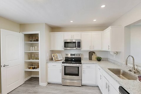 A kitchen with white cabinets and a stainless steel oven.