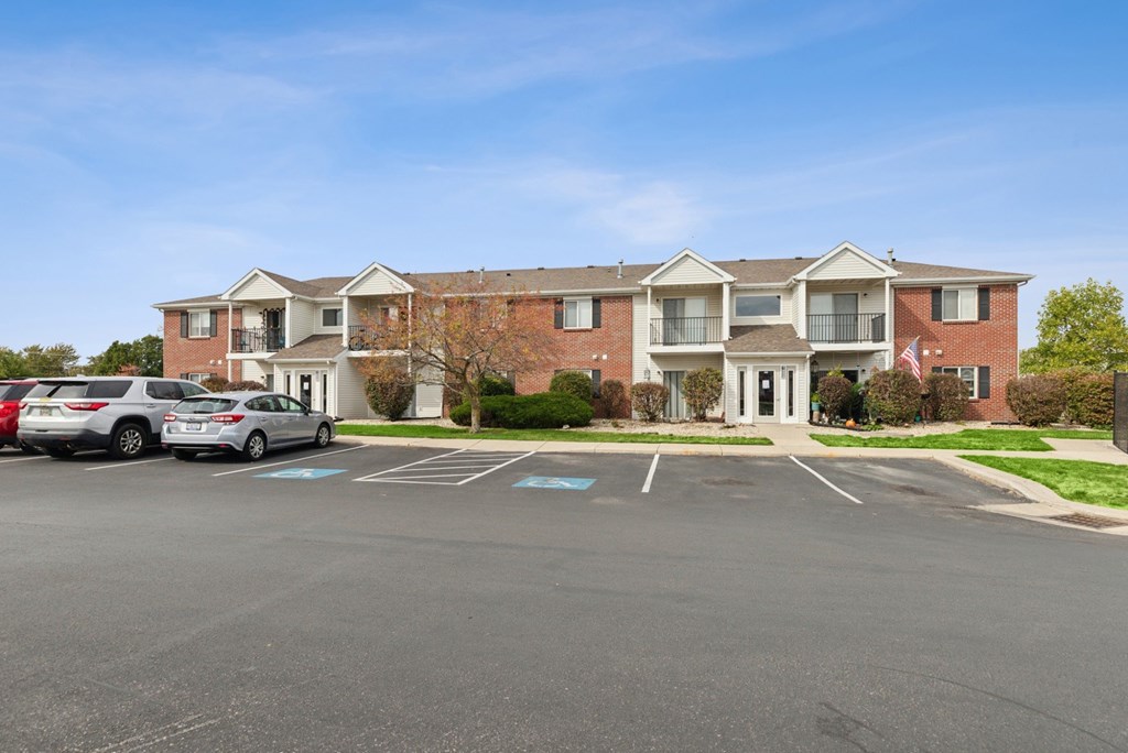 A large red brick building with a parking lot in front.