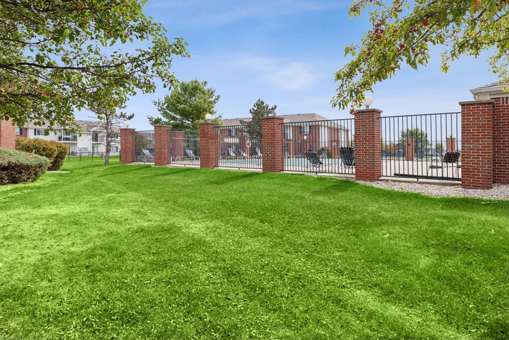 A green lawn with a fence and a building in the background.