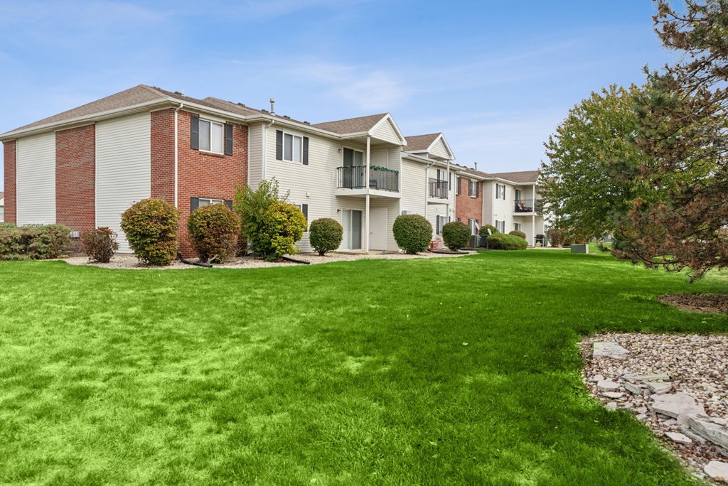 A row of apartment buildings with green lawns in front.