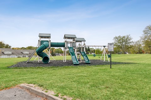 A playground with a green slide and a white sign.