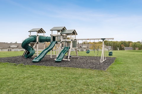 A playground with a green slide and a white structure.