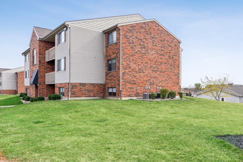 A red brick building with a green lawn in front.