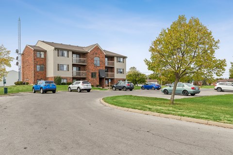 A large apartment building with cars parked in front.