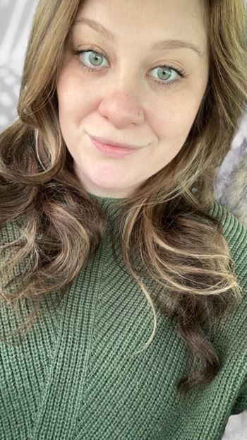 a woman with long hair and green eyes and a green sweater