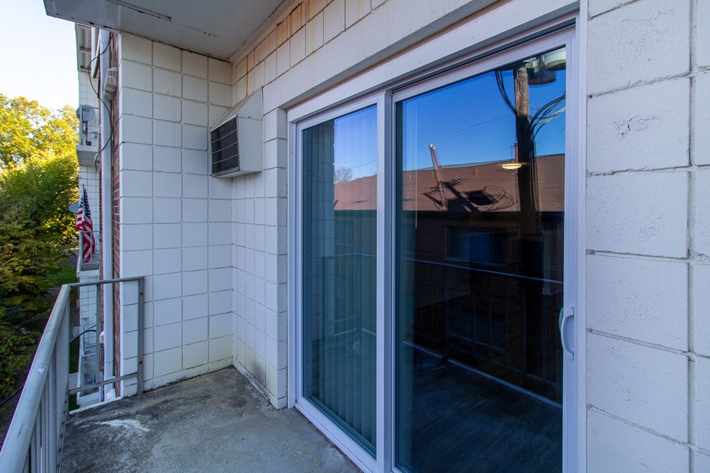 a balcony with a large glass door and a white tile wall