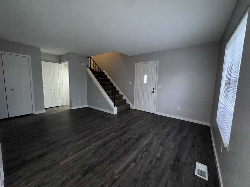 an empty living room with wood floors and a staircase