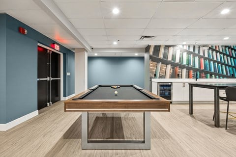 Recreation room with pool table and bookshelf wall at The Landing Apartments, Ohio