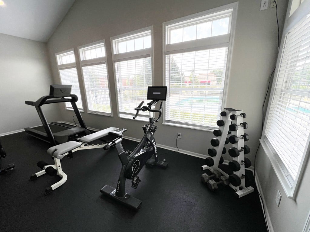 a gym with exercise equipment in a room with windows a gym with exercise equipment in a room with windows at Traditions at Slate Ridge, Reynoldsburg Ohio