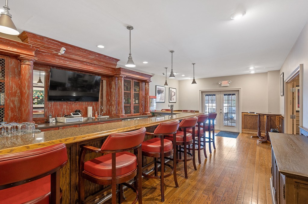 a bar with red chairs in a room with a television at Indian Creek Apartments*, Ohio