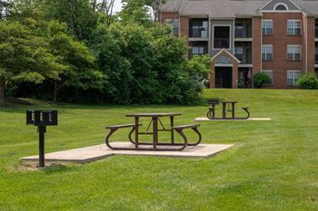 Picnic table and two benches in a grassy area with an apartment building in the background  at Indian Lookout, West Carrollton