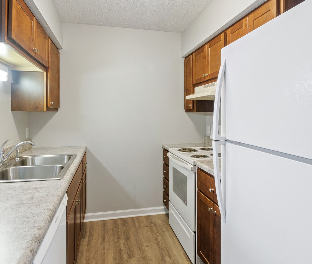an empty kitchen with white appliances and wooden cabinets