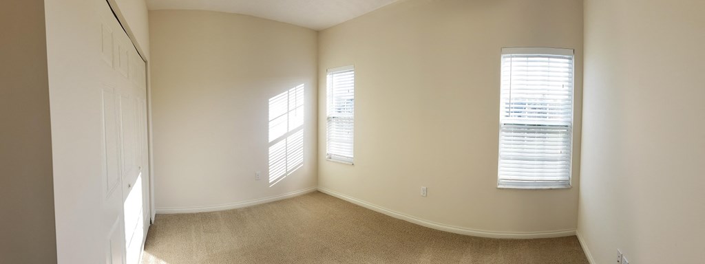 an empty room with two windows and a door