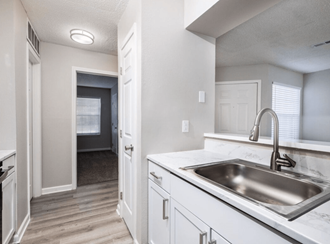 an empty kitchen with a sink and a door to a hallway