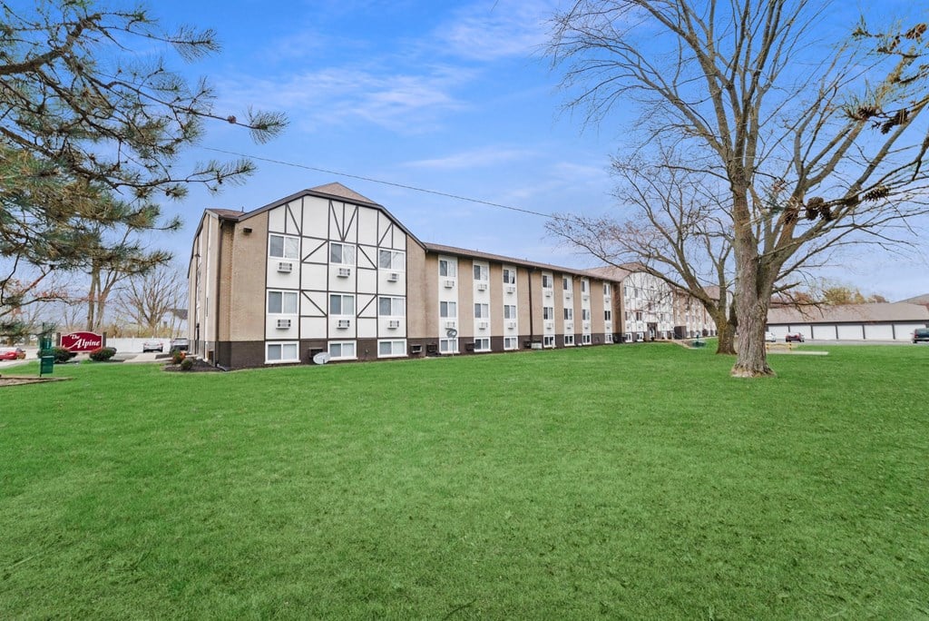A large grassy field in front of a building. A large grassy field in front of a building at The Alpine Apartments, Kettering, OH, 45429